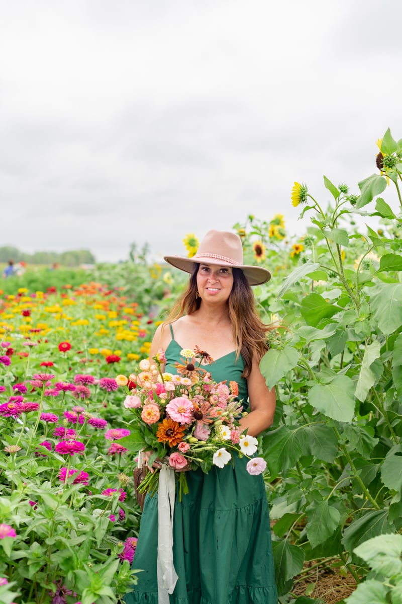 Christy Heckathorn in a green dress and brown hat holding flowers.
