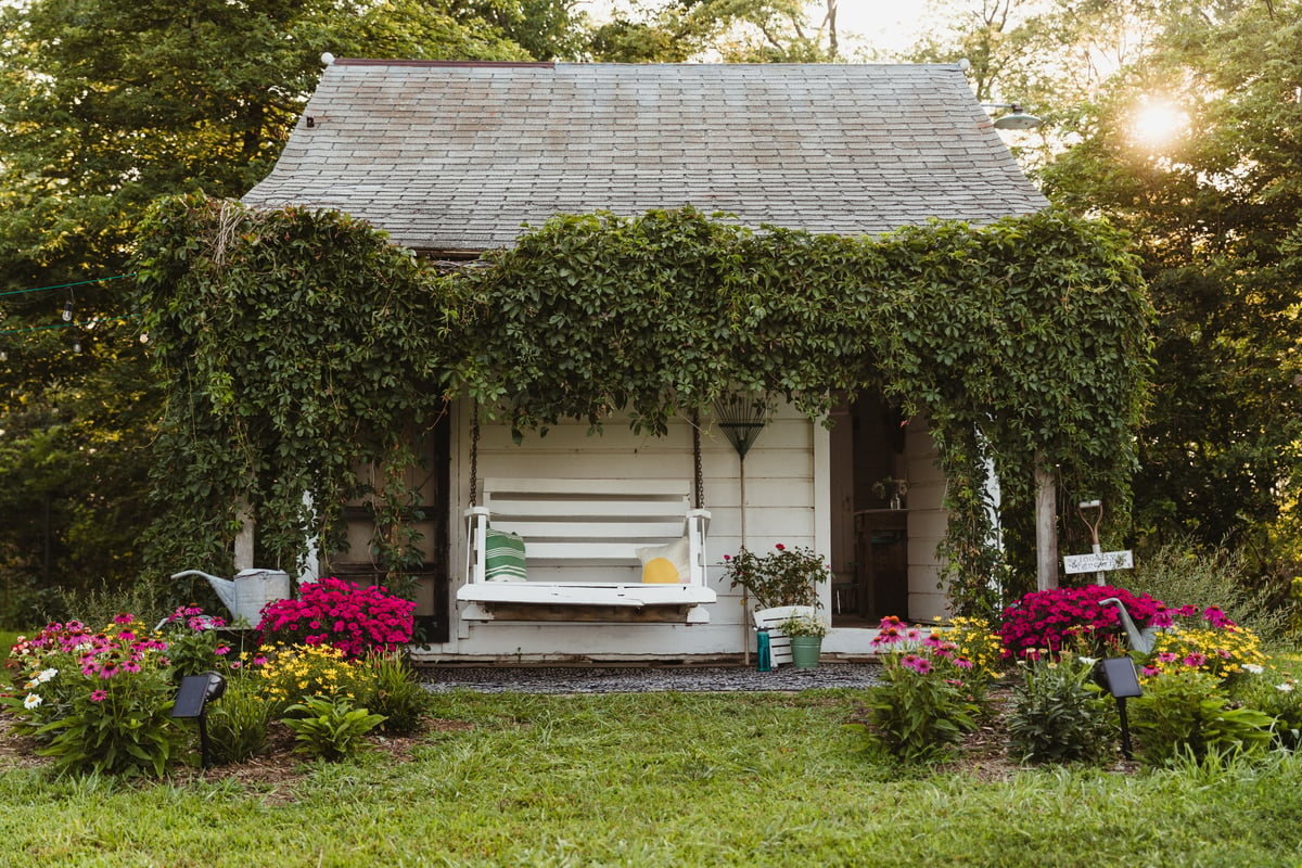 Thelma's charming summer kitchen. The serene porch covered in greenery and a white porch swing complete the cozy feel.