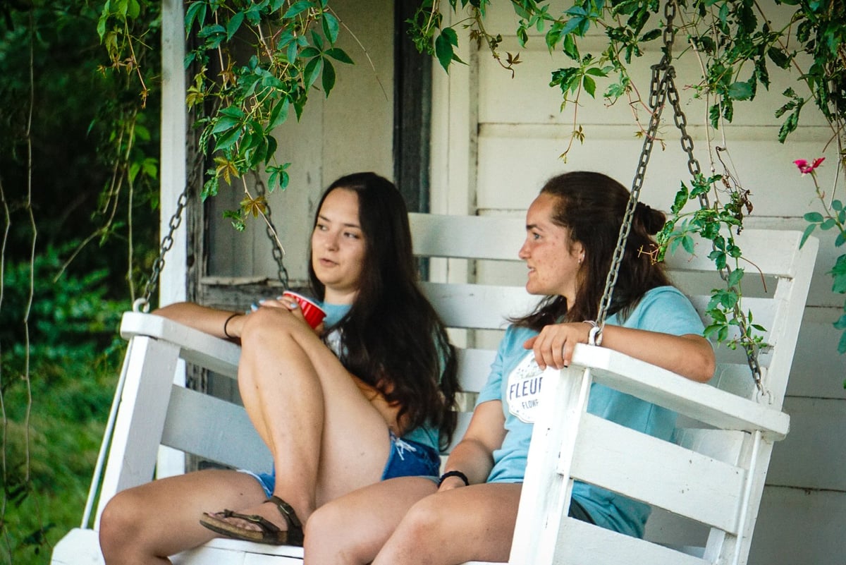 Two girls sitting on the porch swing at Thelma's Summer Kitchen.