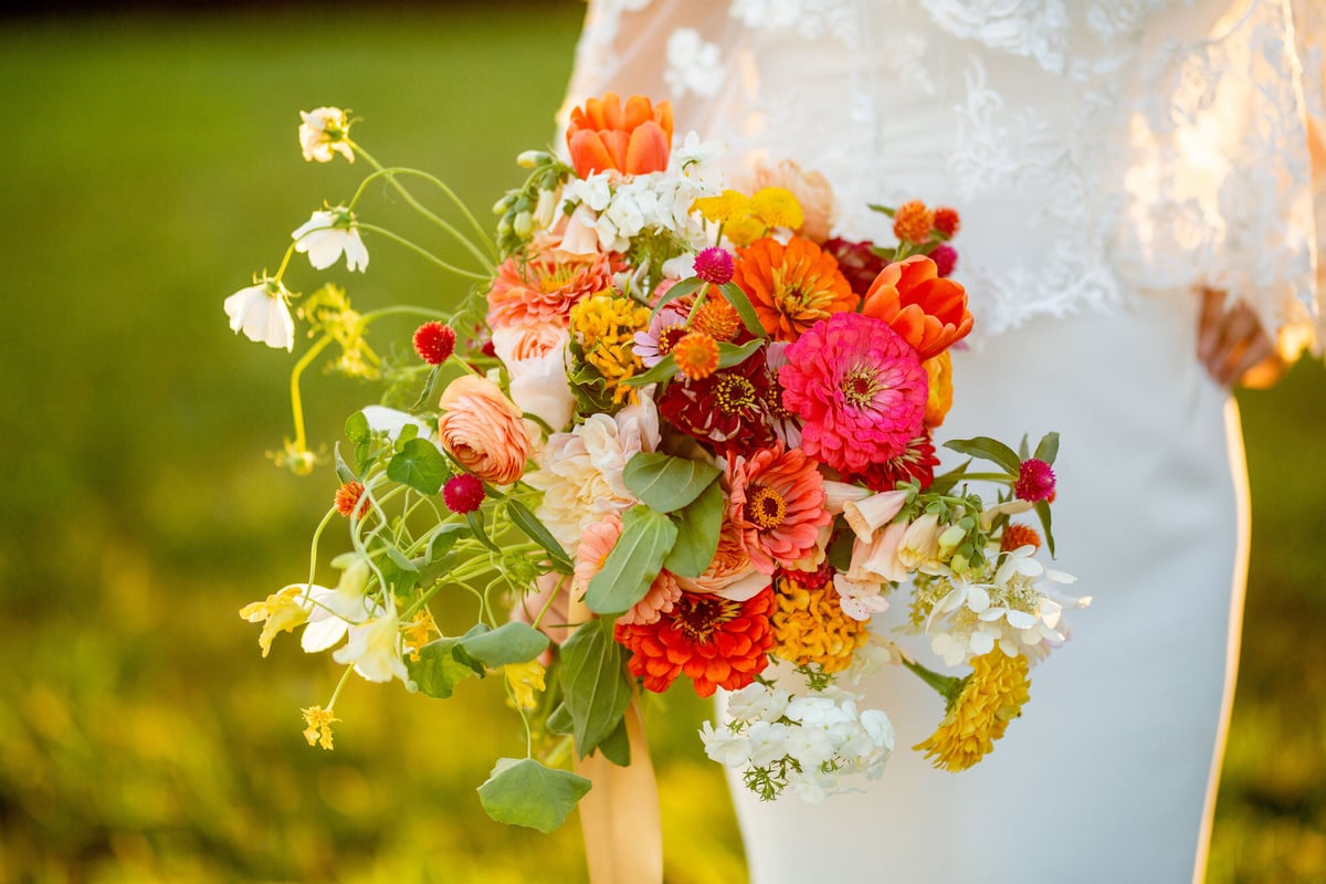 Close up of a bride's floral bouquet of pink, red, and orange flowers.
